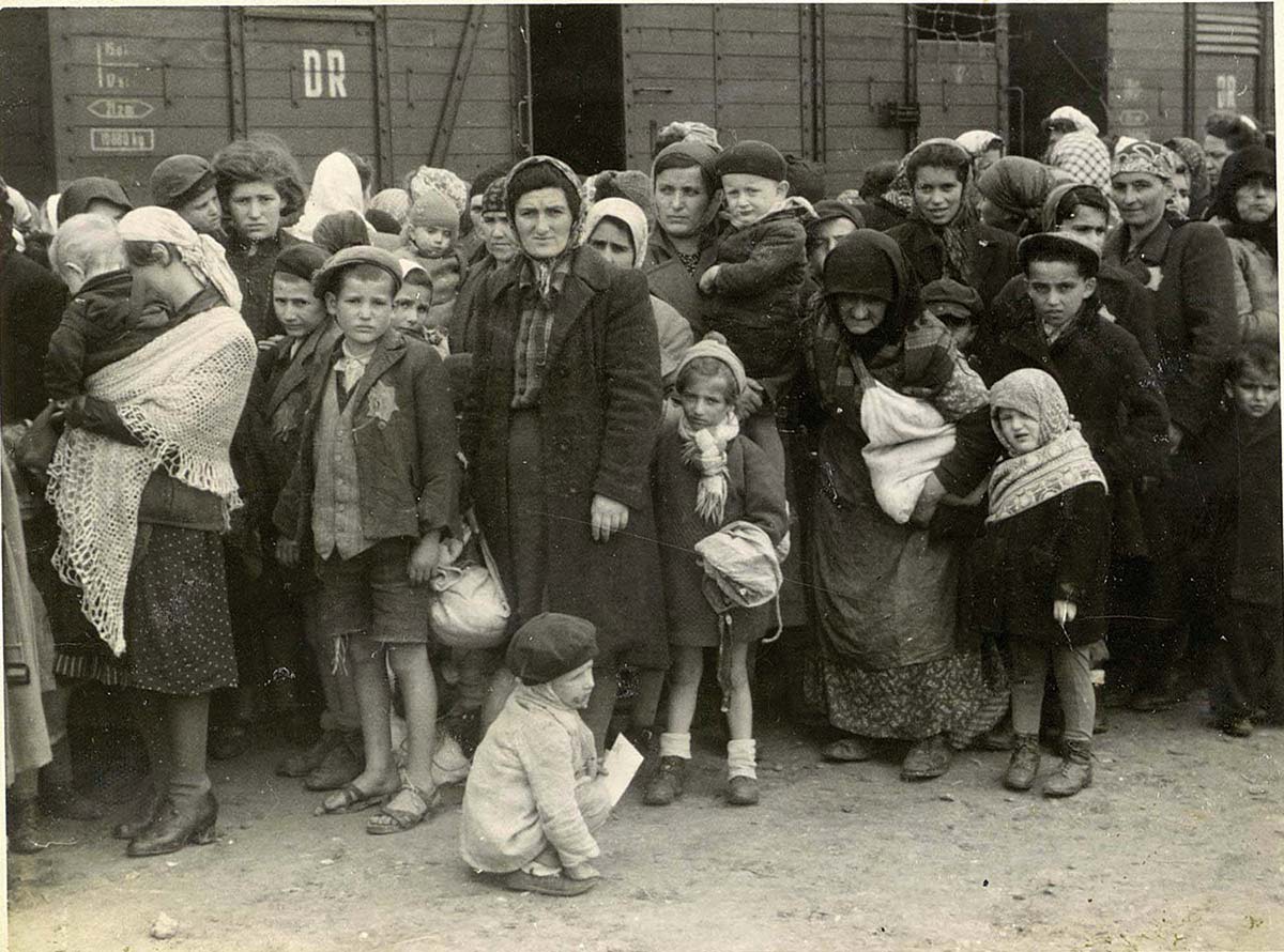 Foto på judiska kvinnor och barn framför en tågvagn
